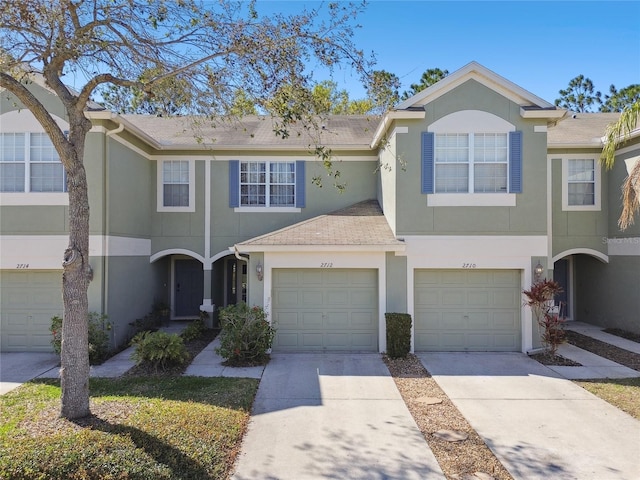 townhome / multi-family property with driveway, roof with shingles, and stucco siding