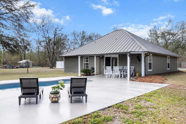 rear view of property with metal roof, a yard, a standing seam roof, and an outdoor pool