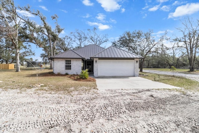 single story home featuring metal roof, an attached garage, brick siding, concrete driveway, and a standing seam roof