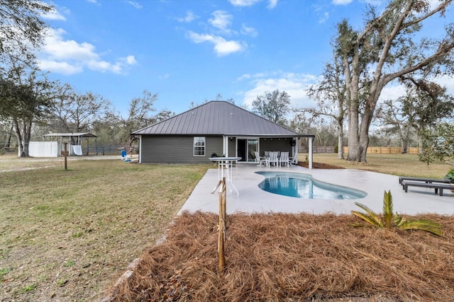 rear view of house with metal roof, fence, a lawn, a fenced in pool, and a patio area