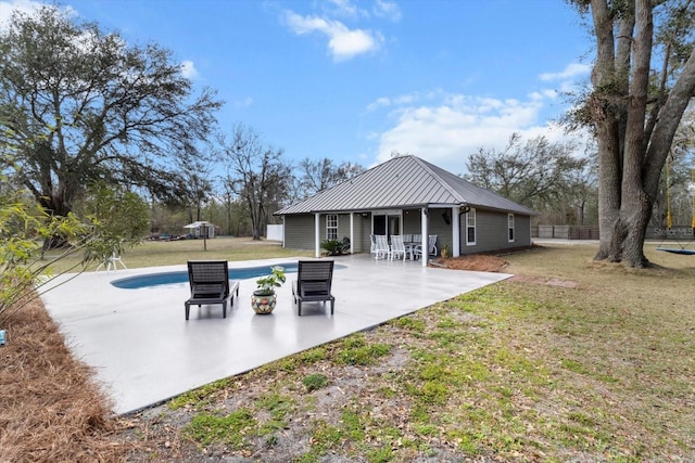 back of property featuring an outdoor pool, a lawn, a patio, metal roof, and a standing seam roof