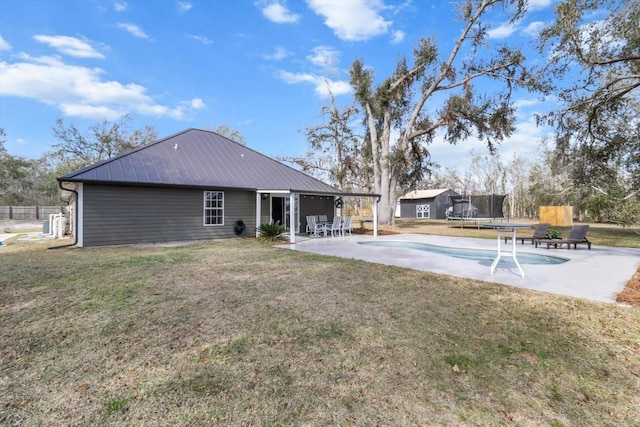 back of house featuring a trampoline, metal roof, a patio area, and fence