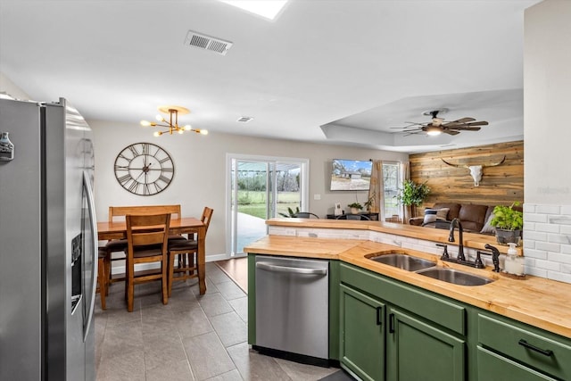 kitchen with visible vents, green cabinets, appliances with stainless steel finishes, a sink, and butcher block countertops