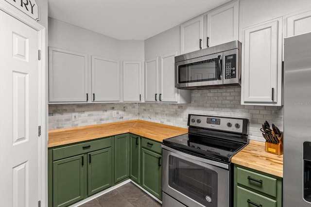 kitchen with green cabinets, butcher block counters, stainless steel appliances, and decorative backsplash