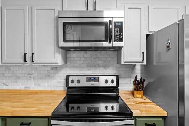 kitchen with appliances with stainless steel finishes, butcher block counters, white cabinetry, and tasteful backsplash