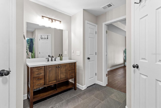 full bath featuring curtained shower, visible vents, vanity, wood finished floors, and baseboards