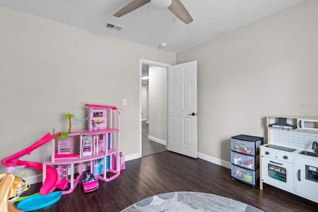 recreation room featuring ceiling fan, dark wood-style flooring, visible vents, and baseboards