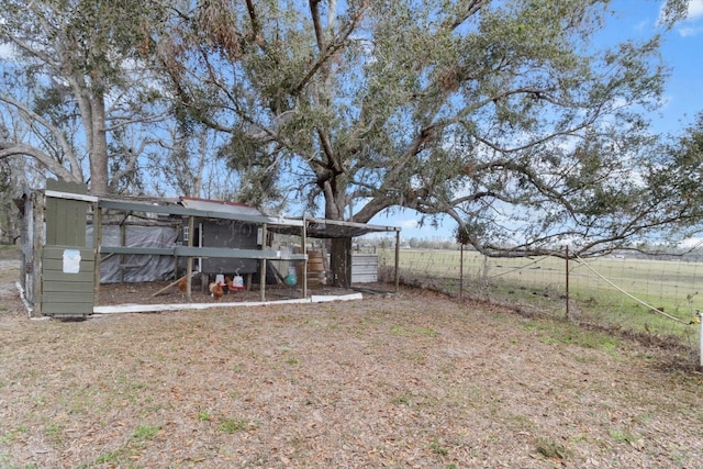 view of yard with an outbuilding, a rural view, fence, and exterior structure