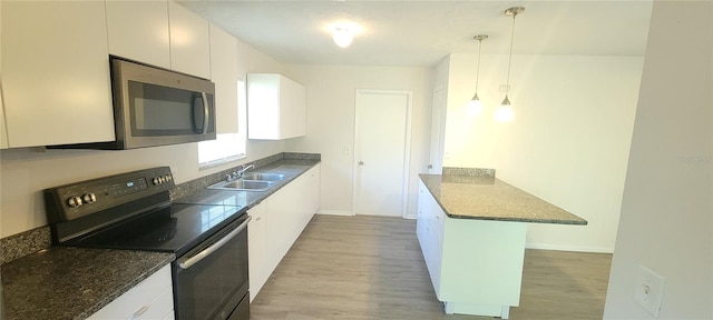 kitchen featuring electric range, light wood-style flooring, a sink, stainless steel microwave, and a peninsula