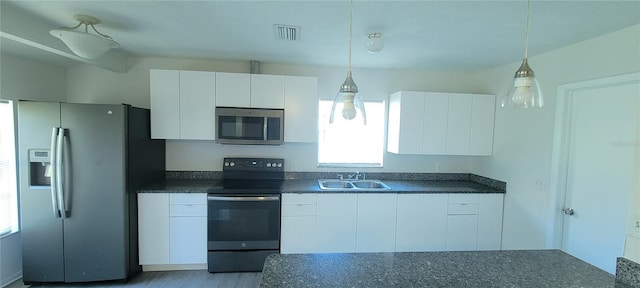 kitchen featuring visible vents, a sink, dark countertops, appliances with stainless steel finishes, and white cabinets