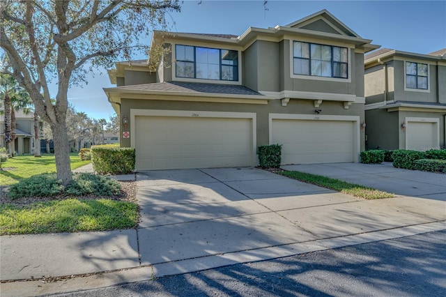 view of property with concrete driveway, roof with shingles, an attached garage, and stucco siding