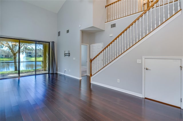 unfurnished living room featuring wood finished floors, visible vents, and baseboards