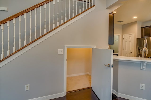 stairway featuring baseboards, visible vents, wood finished floors, and recessed lighting