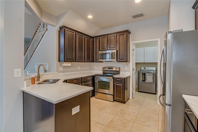 kitchen featuring dark brown cabinetry, stainless steel appliances, a sink, visible vents, and washer / clothes dryer