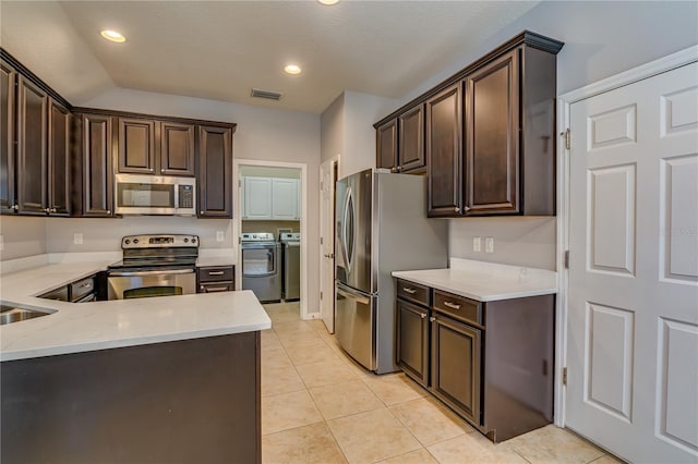 kitchen featuring appliances with stainless steel finishes, visible vents, dark brown cabinetry, and washer and clothes dryer