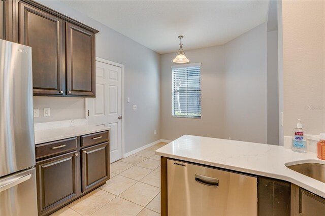 kitchen featuring appliances with stainless steel finishes, dark brown cabinetry, hanging light fixtures, and light tile patterned floors