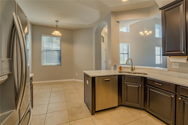 kitchen with appliances with stainless steel finishes, light countertops, dark brown cabinets, a sink, and light tile patterned flooring