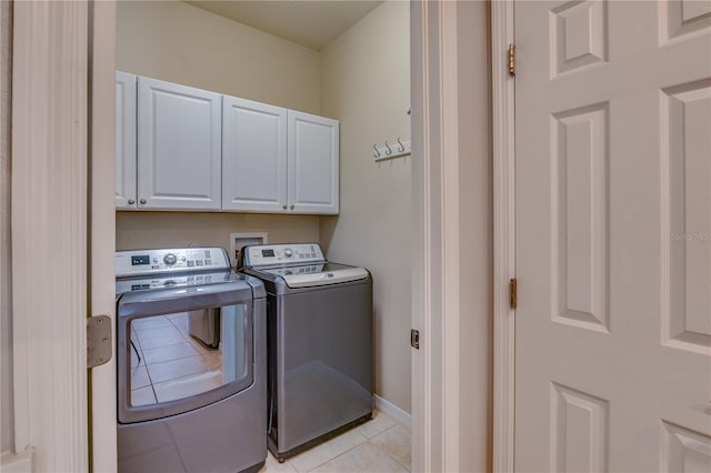 laundry area featuring light tile patterned floors, baseboards, cabinet space, and washer and dryer