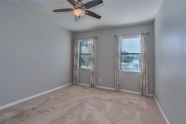 empty room featuring carpet floors, visible vents, ceiling fan, and baseboards