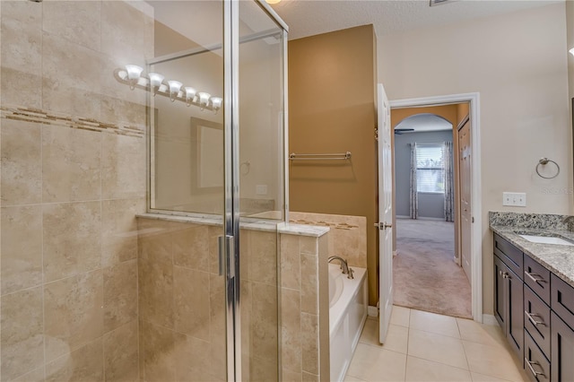 full bath with a stall shower, tile patterned flooring, a garden tub, and vanity