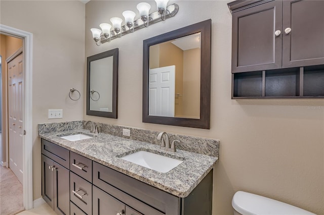 full bath with double vanity, a sink, and toilet