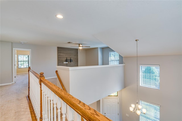 hallway with baseboards, light carpet, visible vents, and an upstairs landing