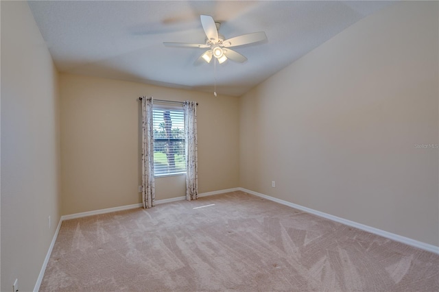 spare room with ceiling fan, baseboards, and light colored carpet