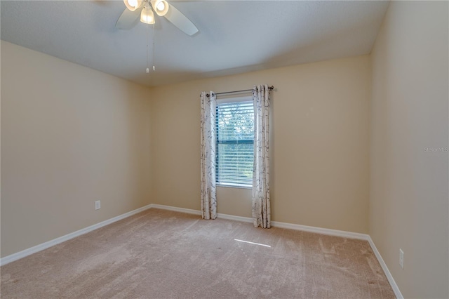 carpeted empty room featuring a ceiling fan and baseboards