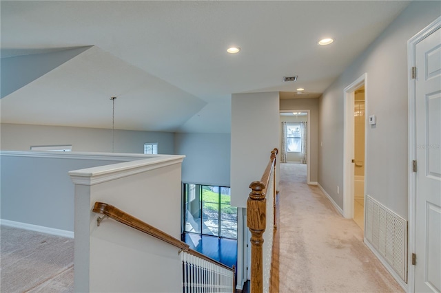 hallway with light colored carpet, visible vents, and an upstairs landing