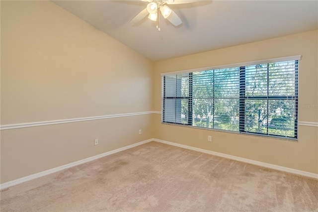 spare room with a ceiling fan, lofted ceiling, light colored carpet, and baseboards