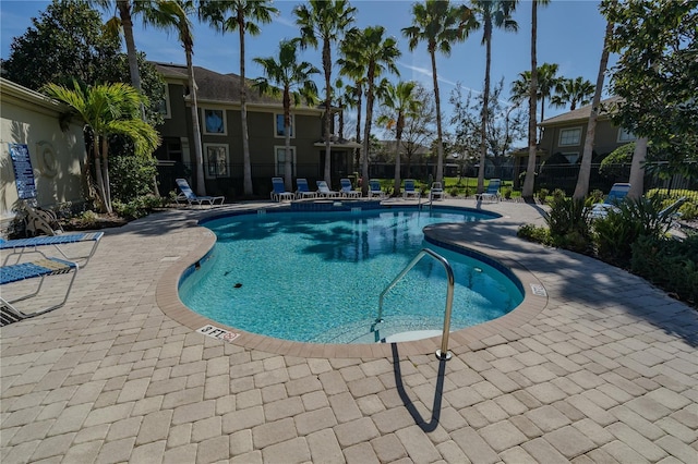 community pool with fence and a patio