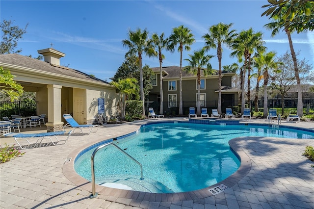 pool with a patio area and fence