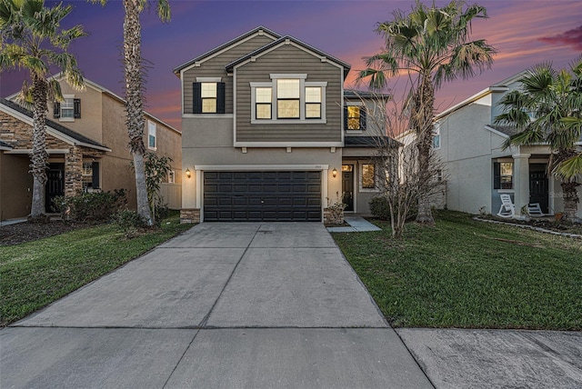 traditional-style home featuring driveway, a lawn, an attached garage, and stucco siding