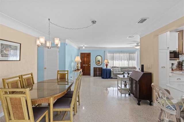 dining room with visible vents, light speckled floor, and ceiling fan with notable chandelier