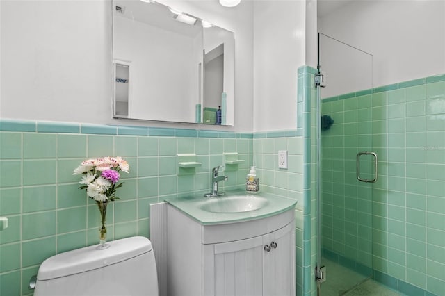 bathroom featuring toilet, a shower stall, vanity, and tile walls