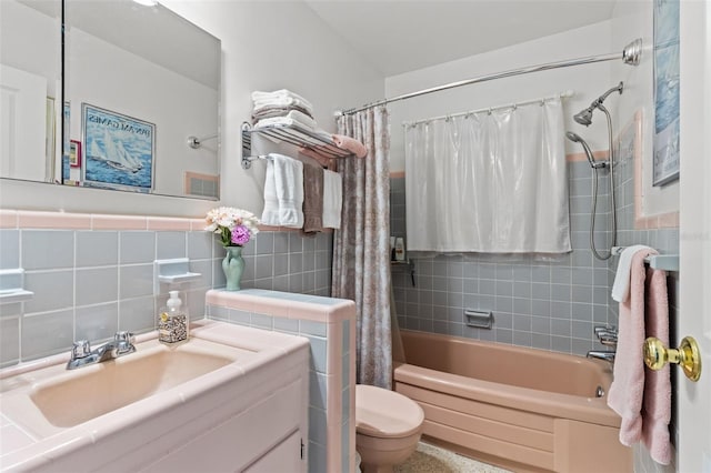 full bathroom featuring toilet, a wainscoted wall, shower / bathtub combination with curtain, vanity, and tile walls