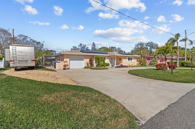 ranch-style home with a garage, concrete driveway, roof mounted solar panels, stucco siding, and a front lawn