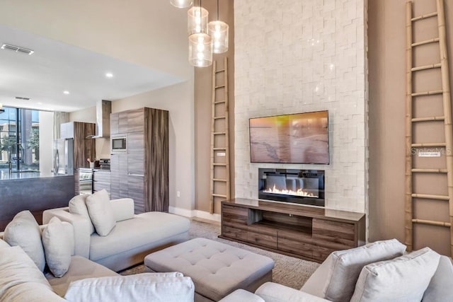 living room with built in shelves, recessed lighting, visible vents, baseboards, and a glass covered fireplace