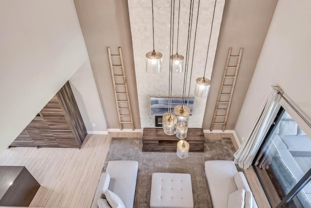 living area with a towering ceiling, baseboards, and wood finished floors