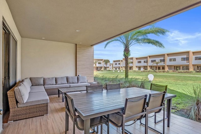 wooden deck featuring outdoor dining space, a yard, a residential view, and an outdoor hangout area