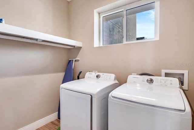 laundry room featuring laundry area, wood finished floors, washing machine and dryer, and baseboards