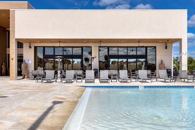 back of property with a patio, a community pool, and stucco siding