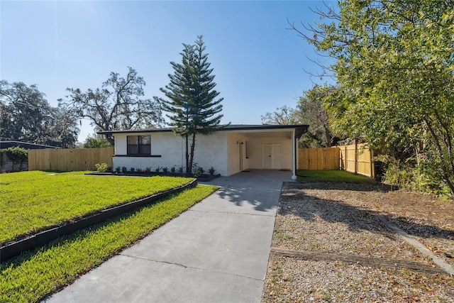 ranch-style house with brick siding, fence, driveway, a carport, and a front lawn