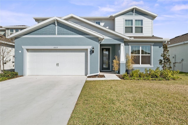 craftsman house with a front yard, concrete driveway, an attached garage, and stucco siding