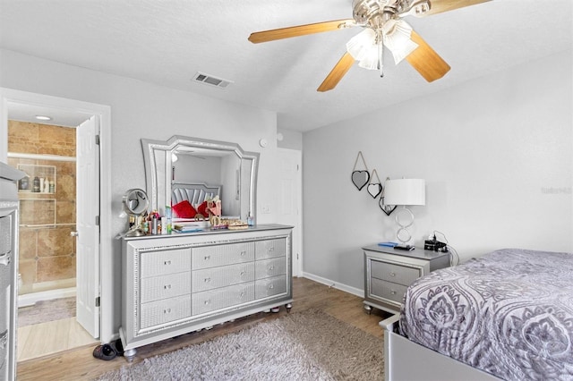 bedroom with visible vents, ceiling fan, connected bathroom, a textured ceiling, and wood finished floors