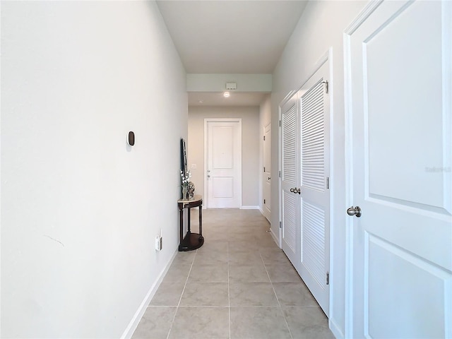 corridor featuring light tile patterned floors and baseboards