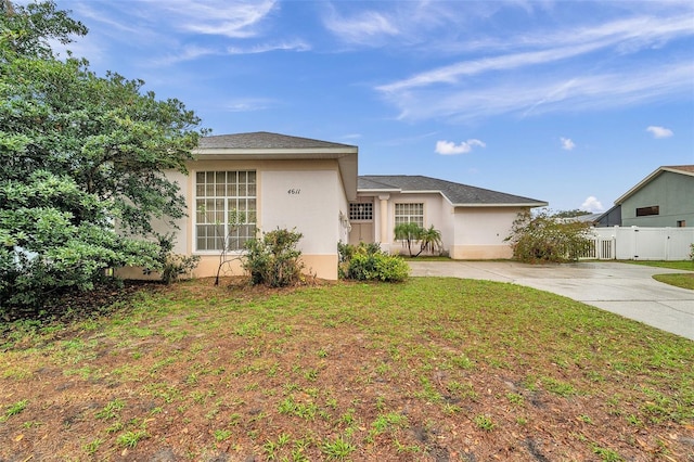 ranch-style house with driveway, a front lawn, and stucco siding