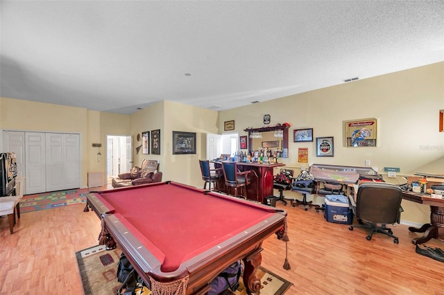 rec room with visible vents, wood finished floors, pool table, a textured ceiling, and a bar