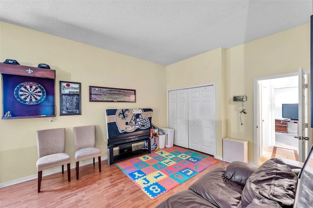 game room featuring a textured ceiling, baseboards, and wood finished floors