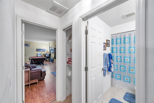 bathroom featuring shower / tub combo, visible vents, and a textured ceiling